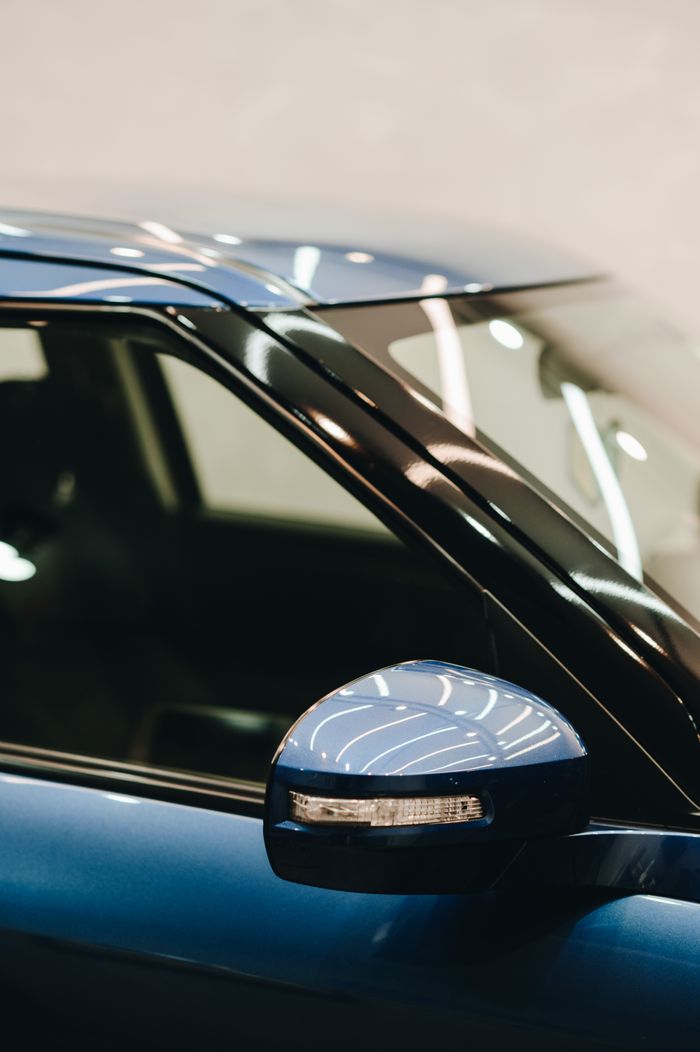 services-01 Detailed view of a blue modern car with a focus on the side mirror and glossy paint.