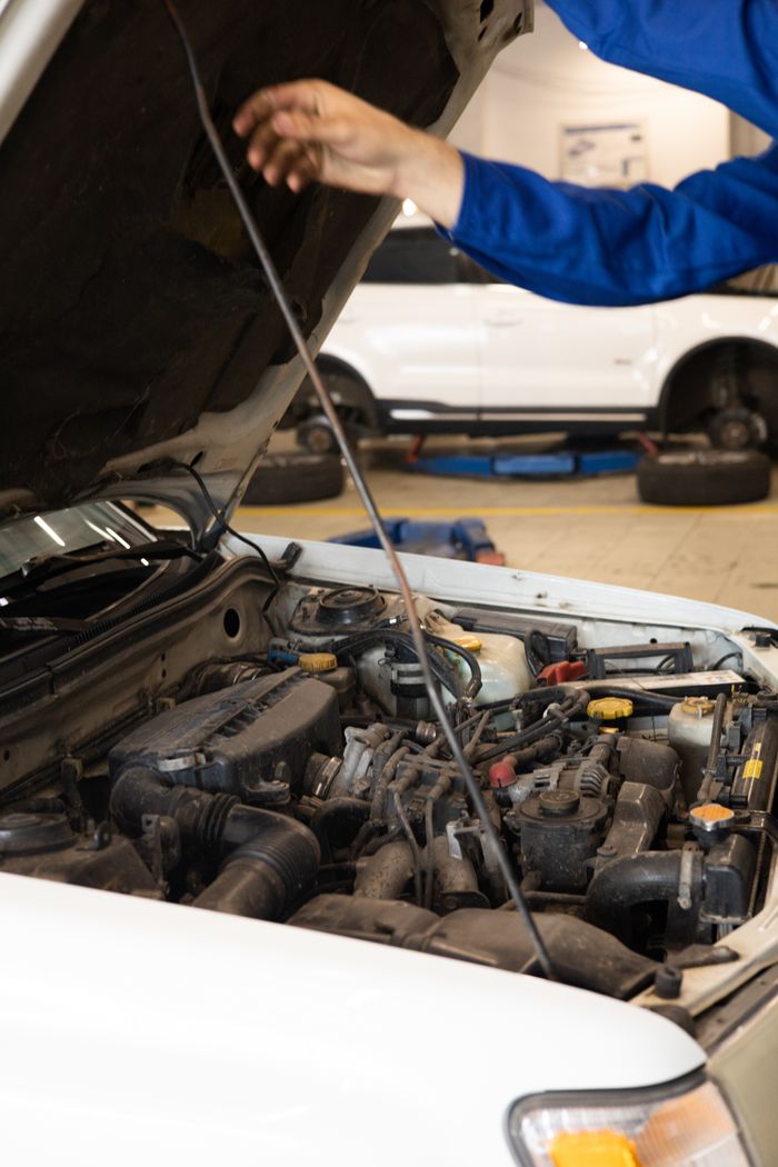 why-choose-us-03 Close-up of mechanic inspecting car engine under open hood in an auto repair shop.